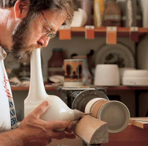 Figure 4. Potter Donald Carpentier applying slip with a “blowing bottle” to a ware attached to a motorized lathe. Ceramics in America, The Chipstone Foundation